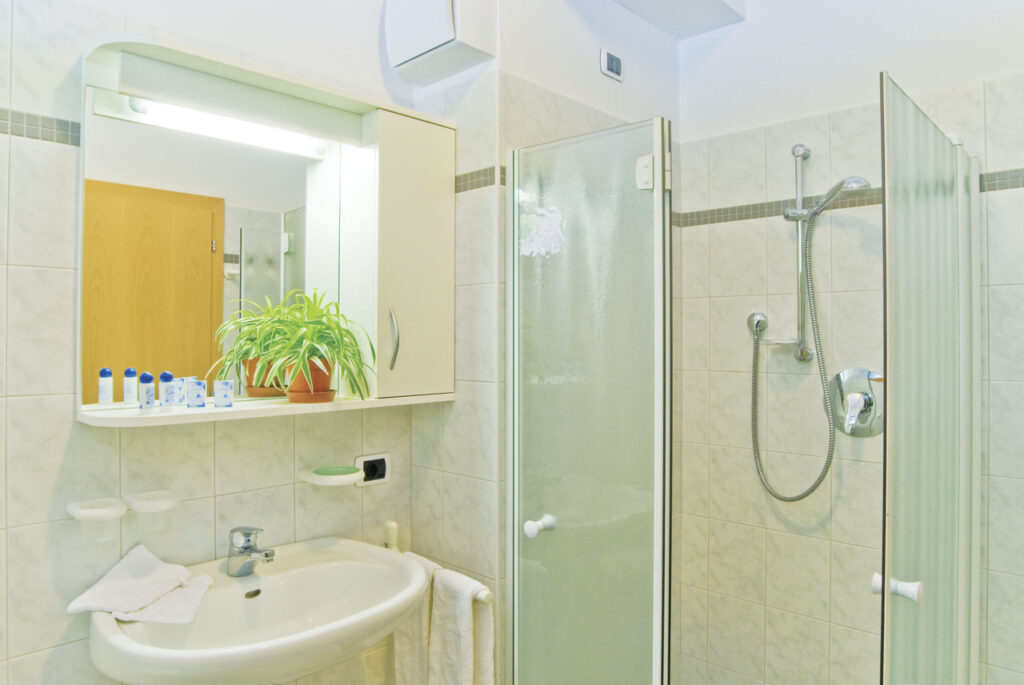 Ein barrierefreies Badezimmer mit einer ebenerdigen Dusche, großem Waschbecken und einem Spiegel mit integriertem Licht.